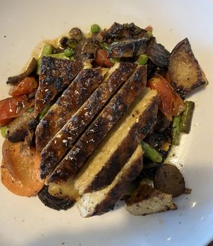 Seared tempeh on a bed of roasted potatoes, asparagus, mushroom, tomatoes and peas.  at South Kitchen + Spirits in Ponte Vedra