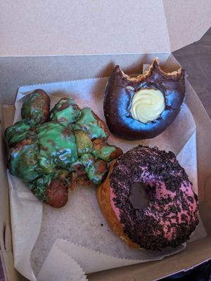 Apple fritter (Green for St. Patrick's), Boston creme, & strawberry glaze + Oreo topping. All yeasted. at Just Fine Donuts in Alexandria