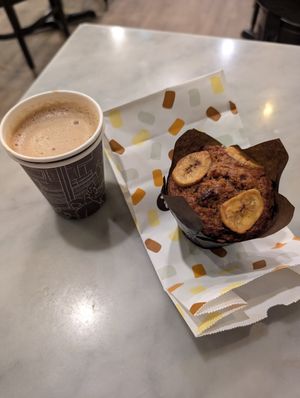 Oat milk flat white with vegan banana muffin at Breka Bakery & Café - Davie in Vancouver