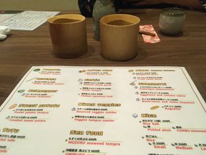 Back side of the vegan menu with pickled cucumber, konjac sashimi and sake in the back  at Hokusai in Fukuoka