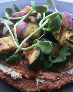 Rawzza - raw pizza - a sprouted lentil and flax crust, layered with sunflower seed pate and marinara with another layer of vegetables roasted (dehydrated) in sundried tomato, olive, garlic and herb pesto, on a bed of chopped fresh spinach and topped with sunflower sprouts. at The Green Eatery in Milton
