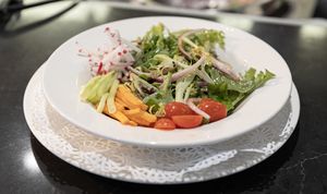 Simple side salad of the day, artistically presented. Carrot, cucumber, radish, red onion, grape tomatoes, and a spectacular house-made dressing over mixed spring greens. at American Harvest Restaurant in Livonia