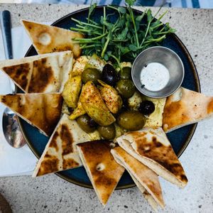 Hummus Olives marinées chaudes, artichaut, zeste d'orange, naan at Les Mauvaises Herbes in Quebec