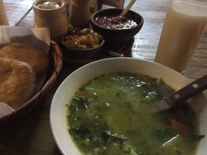 Veggie soup, warm bread, sesame drink, and condiments  at Condor Cafe in Sucre