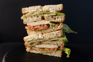 Club Sandwich - Two-tier whole-grain sandwich with grilled tofu, lettuce, tomatoes, crispy BBQ tofu bacon, mayo, dijon mustard and pickles. at Nabati Bistro in Dubai