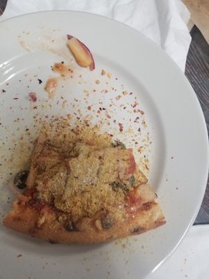 Daughter put a dash of red pepper and dash out nutritional yeast on my slice. /s at Vegan Pizza in Garden Grove