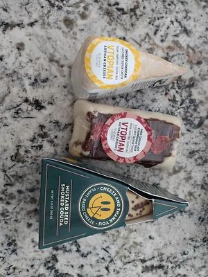 showcases v topian smokey cheddar, v topian dark chocolate strawberry brie, and mustard seed smoked gouda. at Vtopian Cheese Shop in Portland