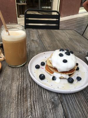 Oat pancakes with blueberries and coconut yoghurt. Oat milk iced latte on the side.   at Berguna Gluten Free in Valencia