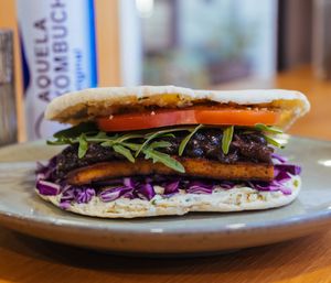 Gently toasted pita with Cremoso herb spread, crisp red cabbage, vacuum-marinated tofu, caramelized red onions, peppery rocket & fresh tomato - delicious symphony!  at Veganaria in Ponta Do Sol