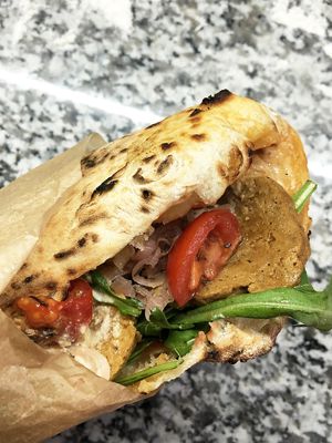 Vegan pizza sandwich: garlic flatbread pizza, tomato sauce, arugula, homemade seitan, pickled cherry, pickled onions, cashew sauce at Daner Pizza in Tbilisi