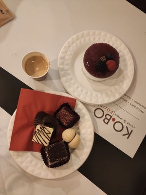 Cheesecake, 3 smaller cakes (raspberry chocolate, italian milk cake and triple chocolate), free biscuit and a espresso macchiato. at Ko.bo Vegan in Milan