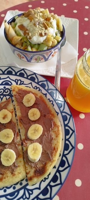Moroccan pancake with chocolate and banana, and fresh orange juice, and tifawin muesli mixed with fruit, so yummy 😋 at Tifawin Cafe in Mirleft