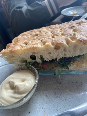 Warm focaccia with pesto, tomato and rucula, served with vegan allioli.  at Palma Stasjonskafe in Sarpsborg