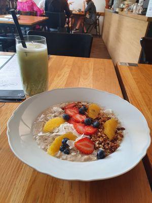 A bowl of oatmeal and a iced matcha latte. at Moment in Prague
