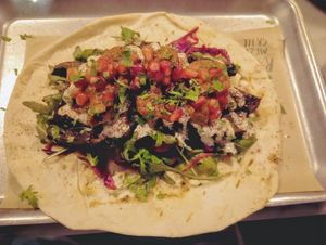 (VE) Mushroom shawarma with pomegranate slaw, rose Harris's, lemon tahini drizzle, wild rocket on a pitta bread base. Filling, tasty, but lacks the proteins. at The Picturedrome in Macclesfield