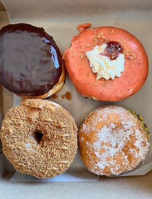 Assorted box of donuts. Clockwise from top left: Boston cream, strawberry shortcake, pistachio cream, Biscoff   at bloomer's in Mississauga
