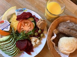 Frühstücksteller - Avocado, rote Beete, Humus, Oliven, Erdnussbutter, Obst und Salat mit Brötchen und O-Saft  at Café May - Eimsbüttel in Hamburg