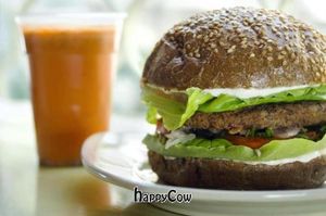 A seductive image of the flag dish, a burger, with a cup of carrot juice in the background. at Buddha Burgers in Haifa