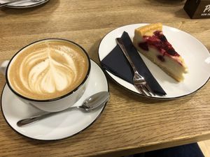 Cappucino (Hafermilch) mit Himbeer-Creme Kuchen/ cappucino (oat milk) with raspberry-cream cake  at Mayersche   in Cologne