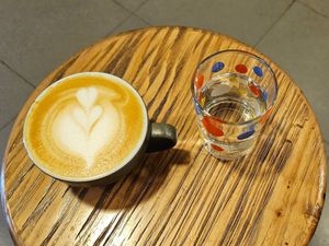 Oatmilk cappuccino, complimentary  water at 84th Brickyard in Hanoi