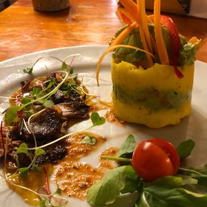 The Causa - traditional Peruvian cold potato pie with avocado mayo, served with mushrooms flambéed in pisco and Peruvian chilli sauce, all on a passion fruit base. at Green Point in Cusco