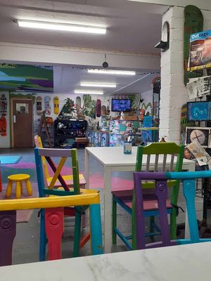 Colourful chairs and the magazine rack to the right with Zines and magazines such as Animal Aid's Outrage. at Doncaster Skate Co-operative in Doncaster
