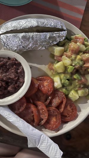 Baked potatoe, avocado salad, beans and grilled tomatoes  at Eva's Cafe and Bar at Mango Inn in Utila