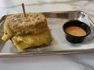 Vegan Biscuit Sandwich- Vegan Red Pepper Aioli, Just Egg, Vegan Smoked Provolone, Vegan Sausage, House Vegan Biscuit. Pictured with an extra side of vegan red pepper aioli.  at Bearcat Baked in New Orleans