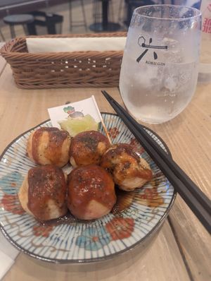 takoyaki 6 portion (i had already eaten 1 oops). I hadn't put mayonnaise on yet. 

Gin & Tonic pictured behind. The lime wedge was from the glass. at Pivot BASE Cafe & Bar ＠Dotonbori in Osaka