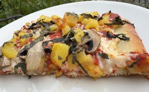 2 slices of 10” Vegan grandma pizza with mushrooms & pineapple with thin julienned slices of fresh basil on top.  at Genova Pizza in Audubon
