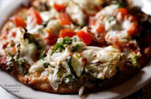 Green Veggie Pizza with Balsamic Tomatoes! A traditional crust with a Creamy Avocado, Marinated Green Veggies including Zucchini, Cabbage, Peppers, and Kale topped with Balsamic Marinated Tomatoes, Melty Mozzarella and Muenster Cheese!  at Sprouts Cafe in Gastonia