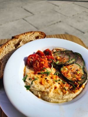 Hummus Plate - Hummus, sautéed cherry tomatoes, sumac cucumber, almond dukkah, 
sweet chili agave, toasted sourdough  at Mitzi Coffee & Brunch in Barcelona