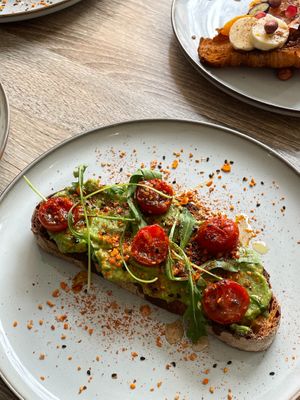 Avocado Toast - Toasted sourdough, mashed avocado, sautéed cherry tomatoes, rocket, 
almond dukkah, sweet chili agave at Mitzi Coffee & Brunch in Barcelona