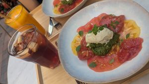 Table comprenant deux assiettes de salade de tomates au pesto et crème de basilic maison et deux boissons végétales : sangria sans alcool et mocktail vitaminé at Chabana in Narbonne