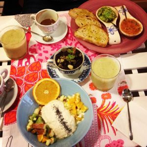 Delicious breakfast of homemade yoghurt with lots of fruit and chia seeds, avocado and tomato toast and fresh pressed kiwi juice at Rayen Vegano in Madrid