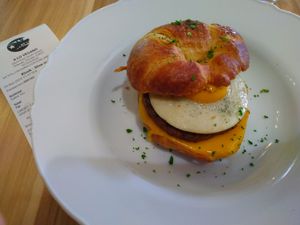 Croissant breakfast sandwich with vegan sunny side up eggs, sausage and cheese. at A Lo Vegano Orlando in Orlando