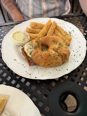 Croissant breakfast sandwich with vegan sunny side up egg and bacon, side of yuca fries  at A Lo Vegano Orlando in Orlando