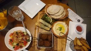 Sharing plate for 2 (€14.50), including salad of choice, 8 pieces of falafel, 4 stuffed vine leaves, 2 spinach pastry rolls, hummus and flatbread. Also with a side of spicy potato wedges. at Umi Falafel - Dame St in Dublin