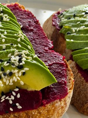 Two slices of country bread toasted in olive oil, beet hummus with hints of lemon, pepper and merquén, avocado slices and sesame seeds  at Bessons Coffee & Bar in Punta Arenas