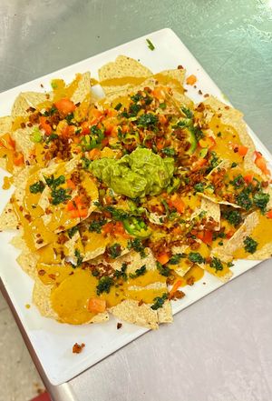 Minachos: corn tortilla chips smothered in a yellow flash nacho cheese sauce, topped with plant chorizo, red bell peppers, green onion, cilantro, jalapeños, crushed red pepper at Hidden Leaf Cafe in Columbus