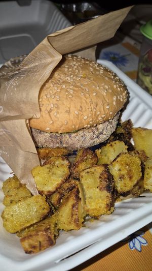 Burger di patate e legumi con bun ai semi di sesamo, condito con mayo all'erba cipollina e insalata di cavola viola e mele. Accompagnato con patate al forno sabbiate. ATOMICO at La Casina di Alice in Livorno