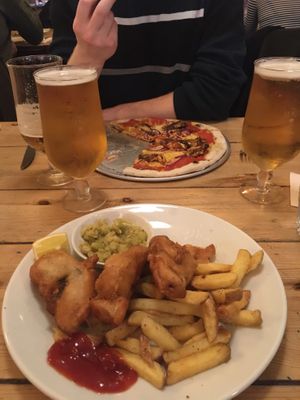 To fish with mushy peas and chips with Korean “chicken” bbq pizza in the background  at Mono in Glasgow
