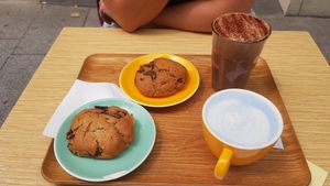 Hot chocolate & spirulina latte with oat milk and two vegan cookies at Bluebird Coffee in Rennes