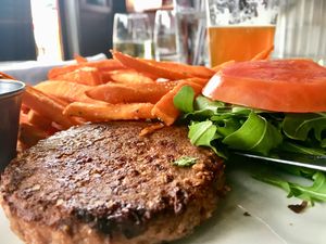 Beyond Meat burger served on a bed of arugula with sweet potato fries  at The Libertine in Dallas