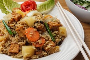 Vegan Pineapple Fried Rice - Thai jasmine rice wok-fried in Madras yellow curry spice pineapple, raisins, cashews, carrots, and onions.  Garnished with lime. at Sukho Thai - Marigny in New Orleans