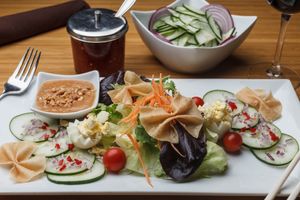 Vegan House Salad - A fresh garden salad of lettuce, cucumber, tomatoes, onion, served with a Thai peanut sauce and garnished with wonton chips.  Optional hard-boiled egg. at Sukho Thai - Marigny in New Orleans