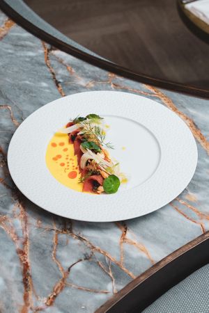 Saffron Tuna Crudo: Lemon cured tuna, saffron and citrus marinade, pickled fennel, chervil, nasturtium, crispy capers, shaved almonds, ñora chili oil at Le Basque in New York City