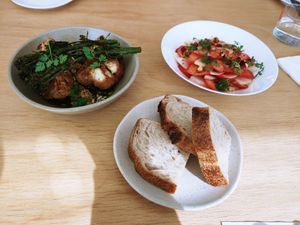 Strawberry salad, cauliflower with herb sauce, and slices of sourdough bread at MitBord in Seoul