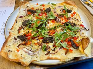 Flammkuchen met  'shpeck' (vegan bacon), truffelsalsa, zoete puntpaprika en rode ui en rucola at Kosmopoliet in Bruges