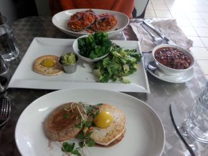 Amazing Sunday brunch. From front to back of photo...The Negg McNish, 4 side dishes (vegan egg white with runny yolk, garlicky greens, house salad with microgreens, black bean and sweet potato chili), and bagel with cream cheese and smoked carrot lox at Doug McNish Public Kitchen in Toronto